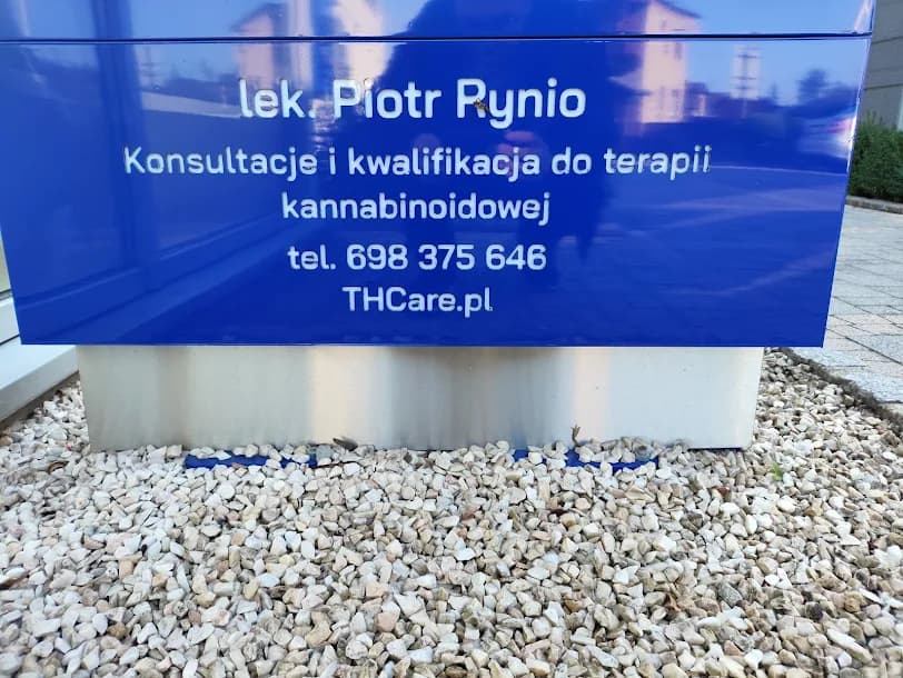Niebieska tablica przy wejściu z napisem: lek. Piotr Rynio, konsultacje i kwalifikacja do terapii kannabinoidowej